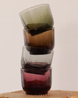 Stacked Pirch espresso glasses in woodland green, amber, smoke, and garnet with artisanal curved design for enhanced flavor and latte art
